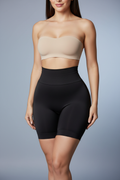 Create a hyper-realistic image of a woman wearing these exact anti-roll high-waist shaping shorts. Same soft grey-blue background. Colombian faja design with reinforced waistband, mid-thigh coverage, black color. Curvy but slim silhouette, snatched waist, smooth hips, lifted butt. Natural confident expression. No branding or logos.